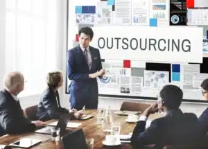 Reunião de negócios com apresentação sobre outsourcing e gráficos de desempenho na parede