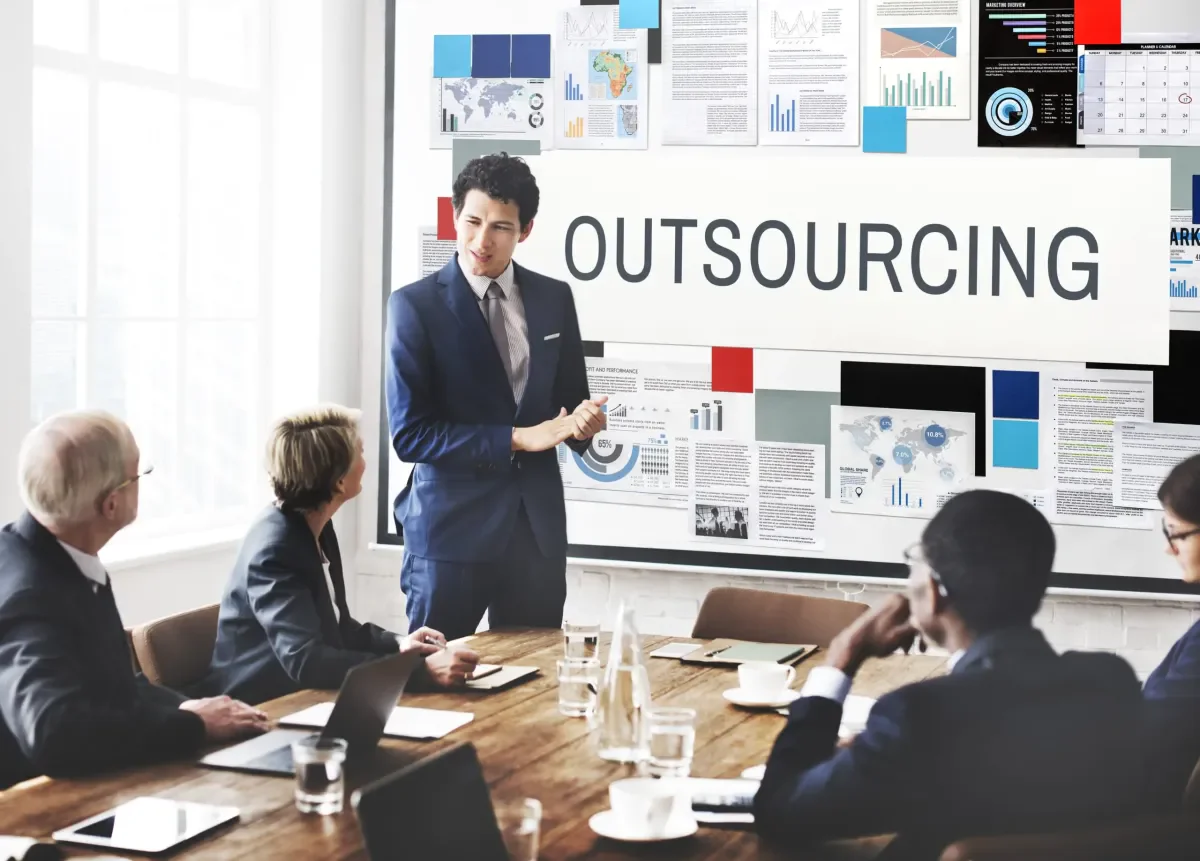 Reunião de negócios com apresentação sobre outsourcing e gráficos de desempenho na parede